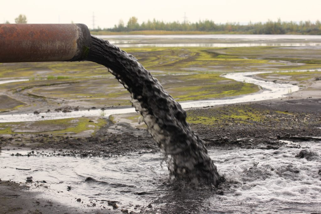 pipe discharging waste into capture pond